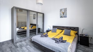 A modern bedroom with a bed, bedside tables, a wardrobe, and a painting on the wall. - Panoramic Top-Floor Downtown Apartment with Citadel & Liberty Statue View (Budapest)