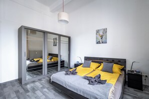 Ein modernes Schlafzimmer mit Bett, Nachttischen, einem Kleiderschrank und einem Bild an der Wand.