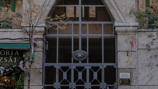 A building facade with a large arched entrance, a balcony with railings, and a flag. - Panoramic Top-Floor Downtown Apartment with Citadel & Liberty Statue View (Budapest)