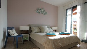 Een slaapkamer met een bed, een stoel, een nachtkastje en een decoratief wandobject.