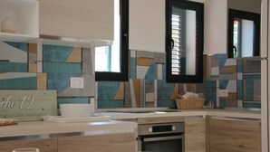 Een moderne keuken met een houten aanrechtblad, een ingebouwde oven en een spatwand met geometrische tegels.