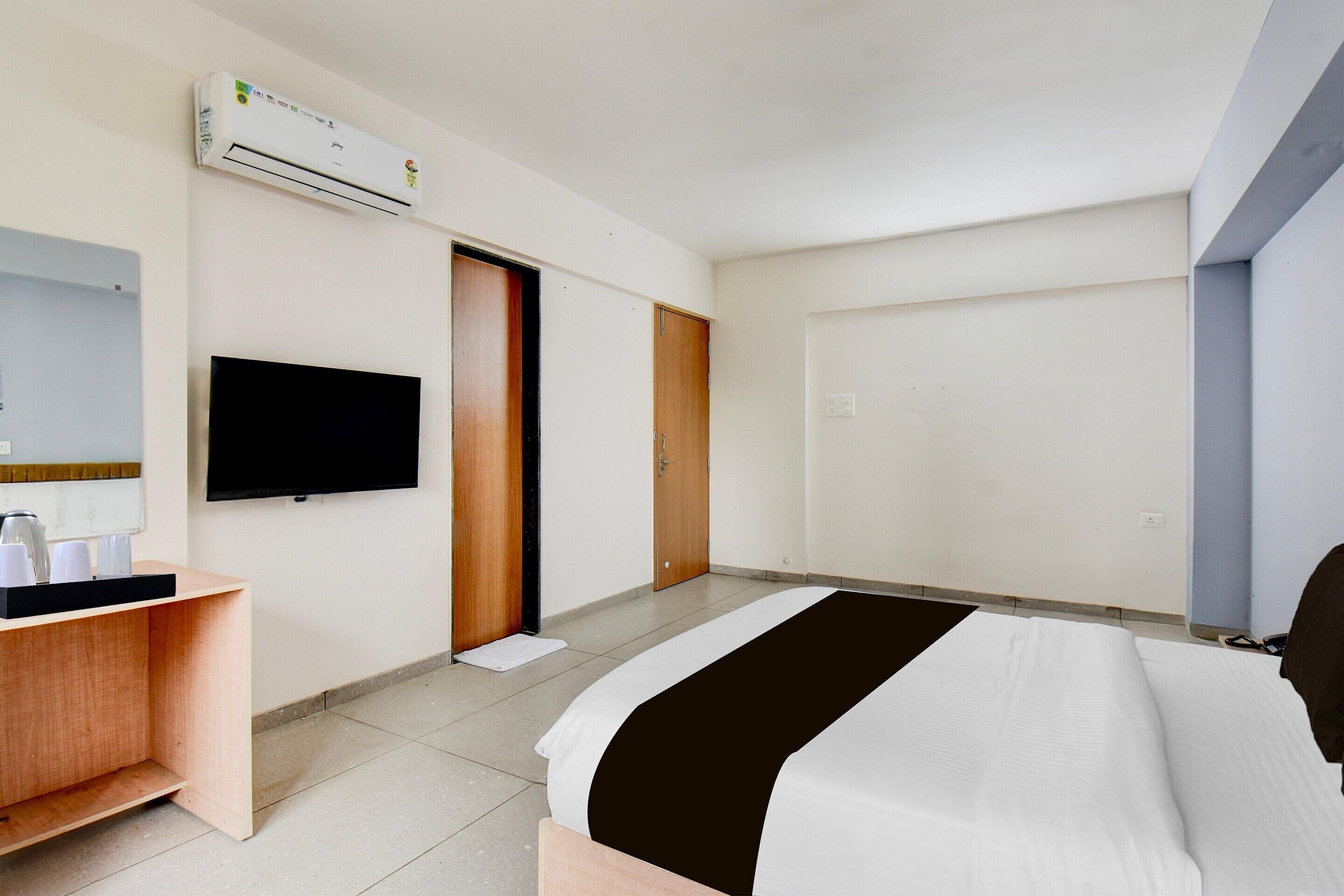 Een hotelkamer met een bed, een televisie, een bureau en een airconditioning.