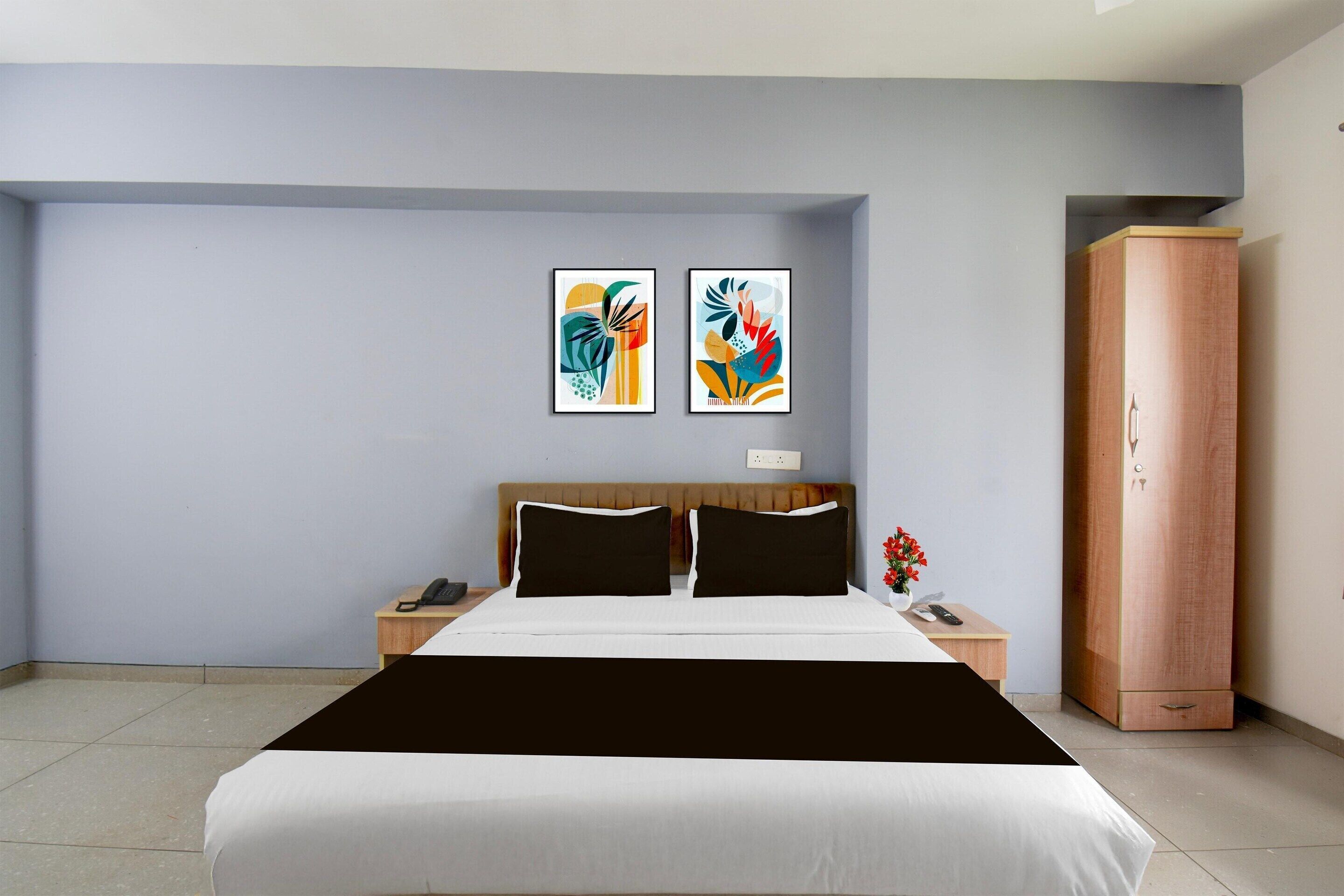 A bedroom with a bed, two bedside tables, a wardrobe, and two abstract paintings on the wall.