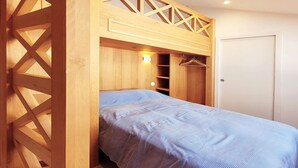 Un dormitorio con una cama litera, un armario de madera y una pequeña estantería.