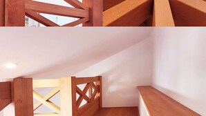 Una escalera de madera con diseño geométrico, una pared blanca y un piso de madera.