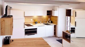 Una cocina moderna con armarios blancos, una encimera de madera y un horno empotrado.