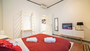 Una habitació d'hotel amb llit, televisió, escriptori i armari.
