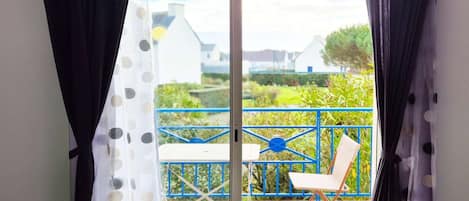A room with a sliding glass door leading to an outdoor patio with a table and chair.