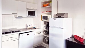 Ett modernt kök med vita skåp, en inbyggd ugn, mikrovågsugn och diskmaskin.