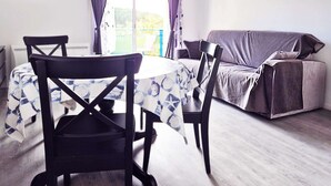 En matplats med ett runt bord och stolar, en soffa och ett fönster med gardiner.