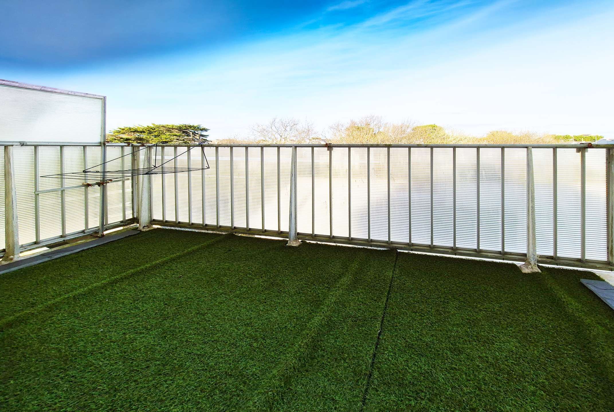 A balcony with artificial grass, metal railing, and a view of a body of water.