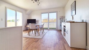 A modern kitchen with a dining area, large windows, and a view of the outdoors. - Le nid de port-lin - Les Gîtes de la Côte d'Amour (LE CROISIC)