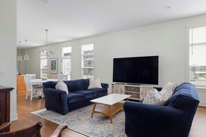 A living room with a sofa, coffee table, TV, and dining area. - Harborside | Golf | Pool | Marina Views (St Joseph)