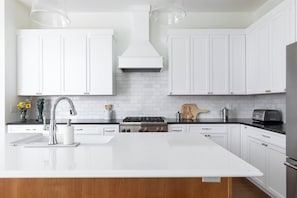 A modern kitchen with white cabinetry, a central island, stainless steel appliances, and a wooden countertop. - Harborside | Golf | Pool | Marina Views (St Joseph)