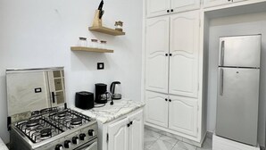 A kitchen with white cabinets, a gas stove, an oven, a refrigerator, and a coffee maker. - Maison Azur à la Marsa Plage (La Marsa)