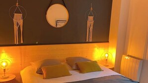 Une chambre à coucher avec un lit, des oreillers, un miroir rond et des lampes fixées au mur.
