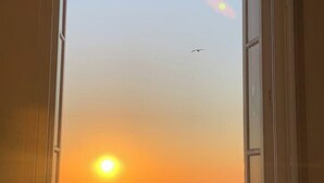 Une fenêtre ouverte donnant sur le coucher de soleil sur l’océan.