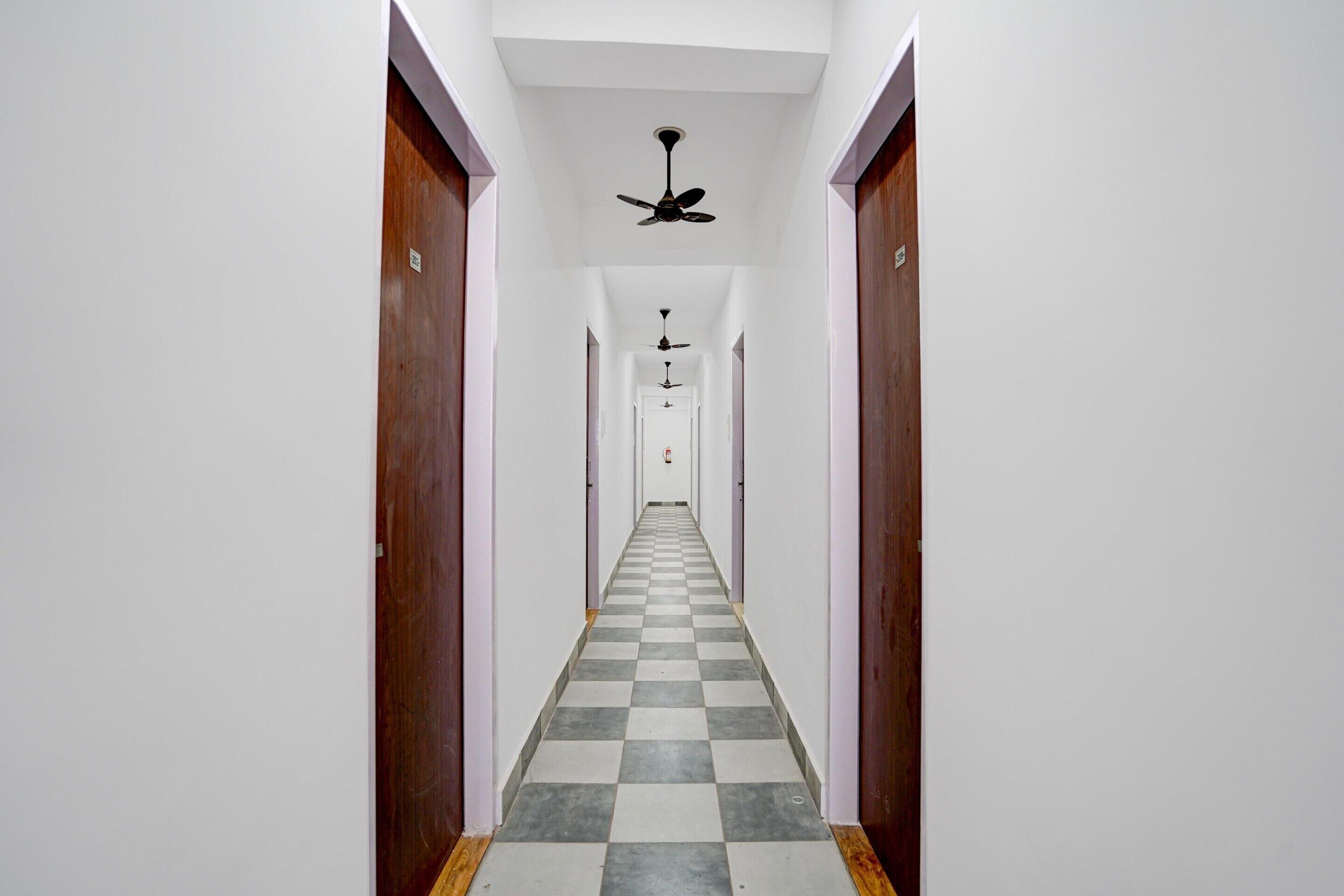 A hallway with checkered flooring, white walls, and wooden doors.
