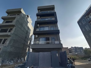 Ein mehrstöckiges Gebäude mit Balkonen, einem verschlossenen Eingang und einem Schild mit der Aufschrift 'PLOT 52 SECTOR 49'.