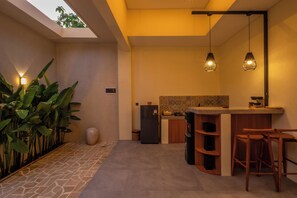 A modern kitchen with a built-in island, pendant lighting, and a stone-tiled floor. - Rinta Villas (Pecatu)