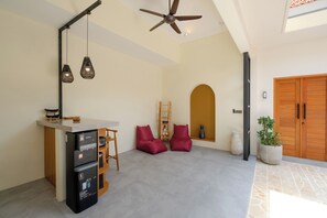 A spacious living area with a kitchen counter, ceiling fan, pendant lights, and a potted plant. - Rinta Villas (Pecatu)