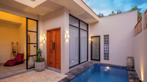 Ein modernes Haus mit Pool, Holztür und rotem Stuhl.