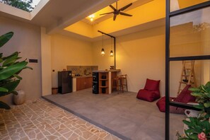 A modern kitchen with a ceiling fan, a dining area with red cushions, and a large window. - Rinta Villas (Pecatu)