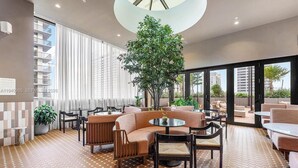 A modern indoor lounge with a central seating area, large windows, and a view of the outside. - Modern Downtown Miami Studio - Rooftop Pool (Miami)