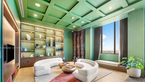 A modern living room with a curved sofa, a coffee table, and a TV mounted on the wall. - Modern Downtown Miami Studio - Rooftop Pool (Miami)