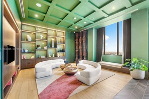 A modern living room with a curved sofa, a coffee table, and a TV mounted on the wall. - Modern Downtown Miami Studio - Rooftop Pool (Miami)