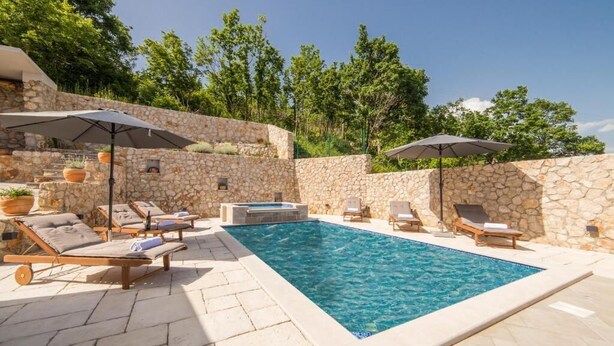 A swimming pool with lounge chairs and umbrellas, surrounded by stone walls and greenery. - Villa Argenta in lovely Aržano, Croatia (Aržano)