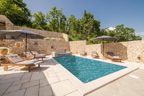 A swimming pool with lounge chairs and umbrellas, surrounded by stone walls and greenery. - Villa Argenta in lovely Aržano, Croatia (Aržano)