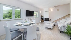 A modern living room with a dining area, a flat-screen TV, and a staircase leading to an upper level. - Villa Argenta in lovely Aržano, Croatia (Aržano)