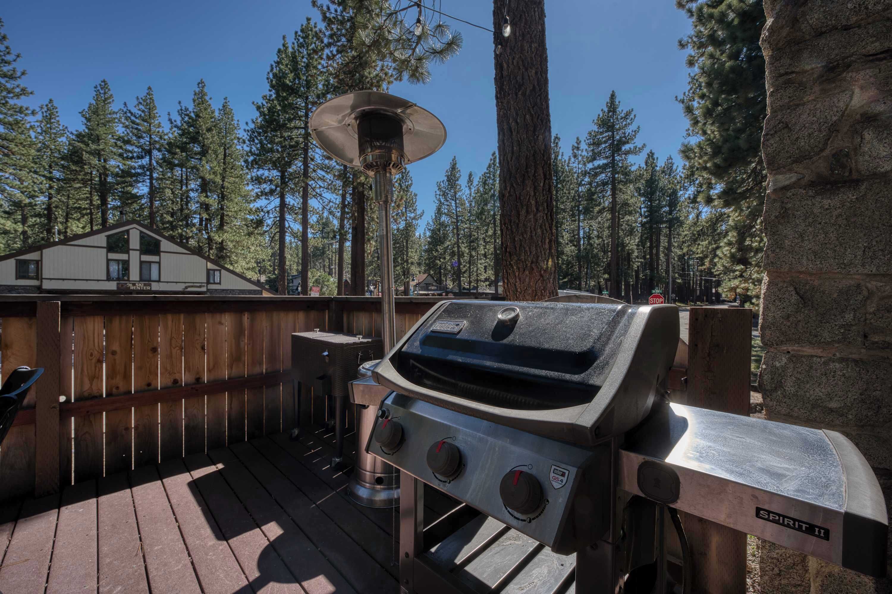 A backyard with a grill, a wooden deck, and a house in the background.