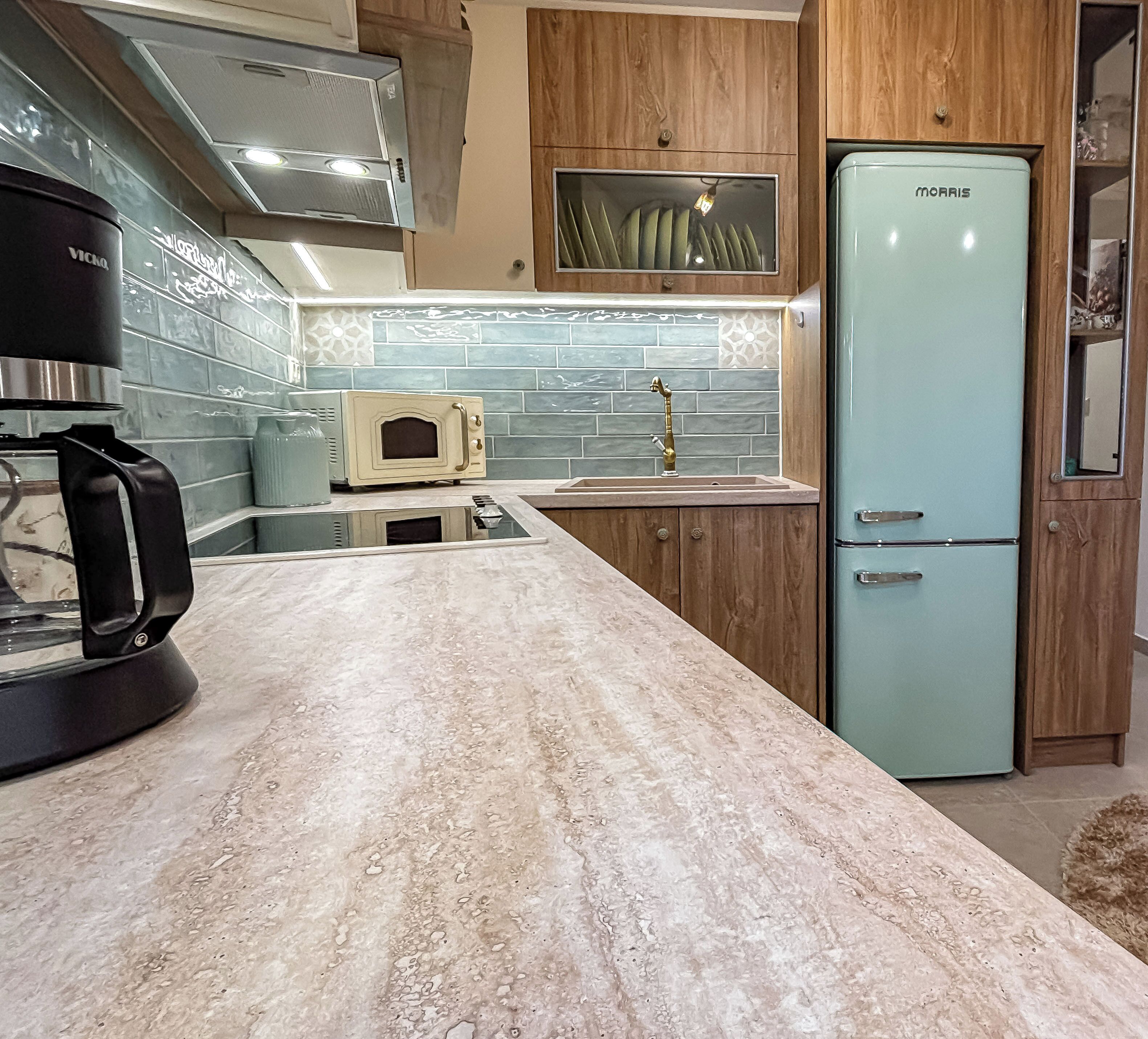A kitchen with a marble countertop, a vintage-style microwave, a refrigerator, and a coffee maker.