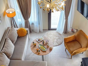 Un salon moderne avec un canapé, un fauteuil, une table basse et un lustre.