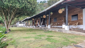 A wooden building with a covered porch, stone pathway, and hanging planters. - Nebula Minca Ecolodge by Xarm Apartments (Santa Marta)