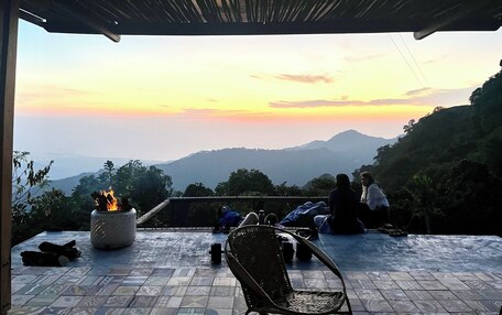 An outdoor seating area with a fire pit, a chair, and a view of the mountains at sunset.