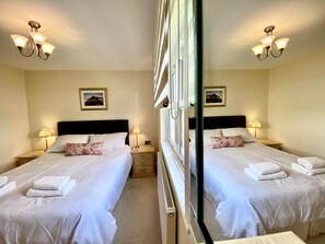 A mirrored room with two beds, bedside lamps, and a framed picture on the wall. - 8 Howrahs Court, Elliott Park, Keswick (Keswick)