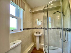 A bathroom with a glass-enclosed shower, a pedestal sink, a window, and a tiled backsplash. - 8 Howrahs Court, Elliott Park, Keswick (Keswick)