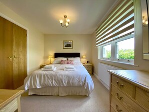 A bedroom with a bed, bedside lamps, a picture on the wall, a window with blinds, and a wooden dresser. - 8 Howrahs Court, Elliott Park, Keswick (Keswick)