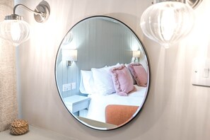 A round mirror reflecting a bed with pillows, a bedside table, and wall-mounted lights. - Brandelhowe, Apartment 1, Derwent House (Portinscale)
