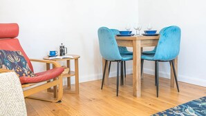 A dining area with a wooden table, two blue chairs, and a red chair with a patterned cushion. - Riverside View, 5 Elm Court, Elliott Park (Keswick)