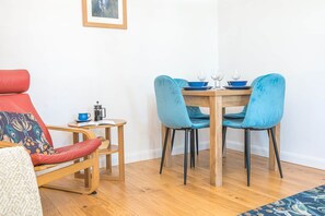 Ein Essbereich mit einem Holztisch, zwei blauen Stühlen und einem roten Stuhl mit gemustertem Sitzkissen.