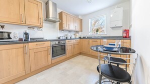 A modern kitchen with wooden cabinets, a built-in oven, a microwave, and a coffee maker. - Riverside View, 5 Elm Court, Elliott Park (Keswick)