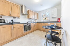 Eine moderne Küche mit Holzausstattung, integriertem Backofen, Mikrowelle und Kaffeemaschine.