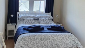 A bedroom with a bed, two bedside tables, a window with curtains, and a wall-mounted picture. - Skiddaw, 20 Greta Grove House (Keswick)