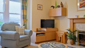 En stue med sofa, fjernsyn, pejs og et lille bord.