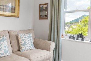 Ein Zimmer mit einer Couch, einer gerahmten Karte und einem Fenster mit Fernglas.