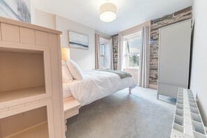 A bedroom with a bed, a wardrobe, a radiator, and a window with curtains. - Withesike, Apartment 2, Derwent House (Portinscale)